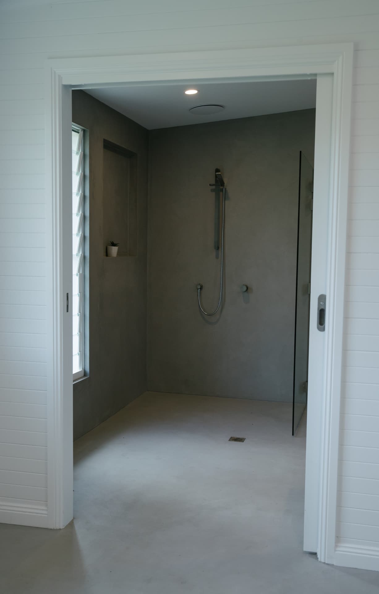 View through a cavity slider into a renovated microcement shower room