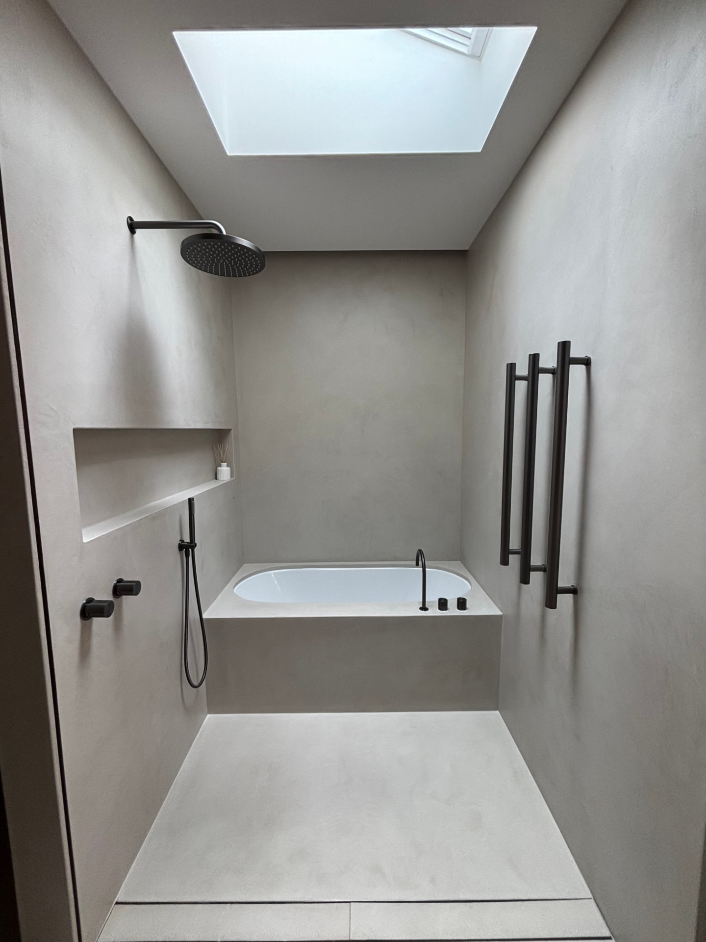 Andrew Place microcement bathroom with an inset bath under a skylight