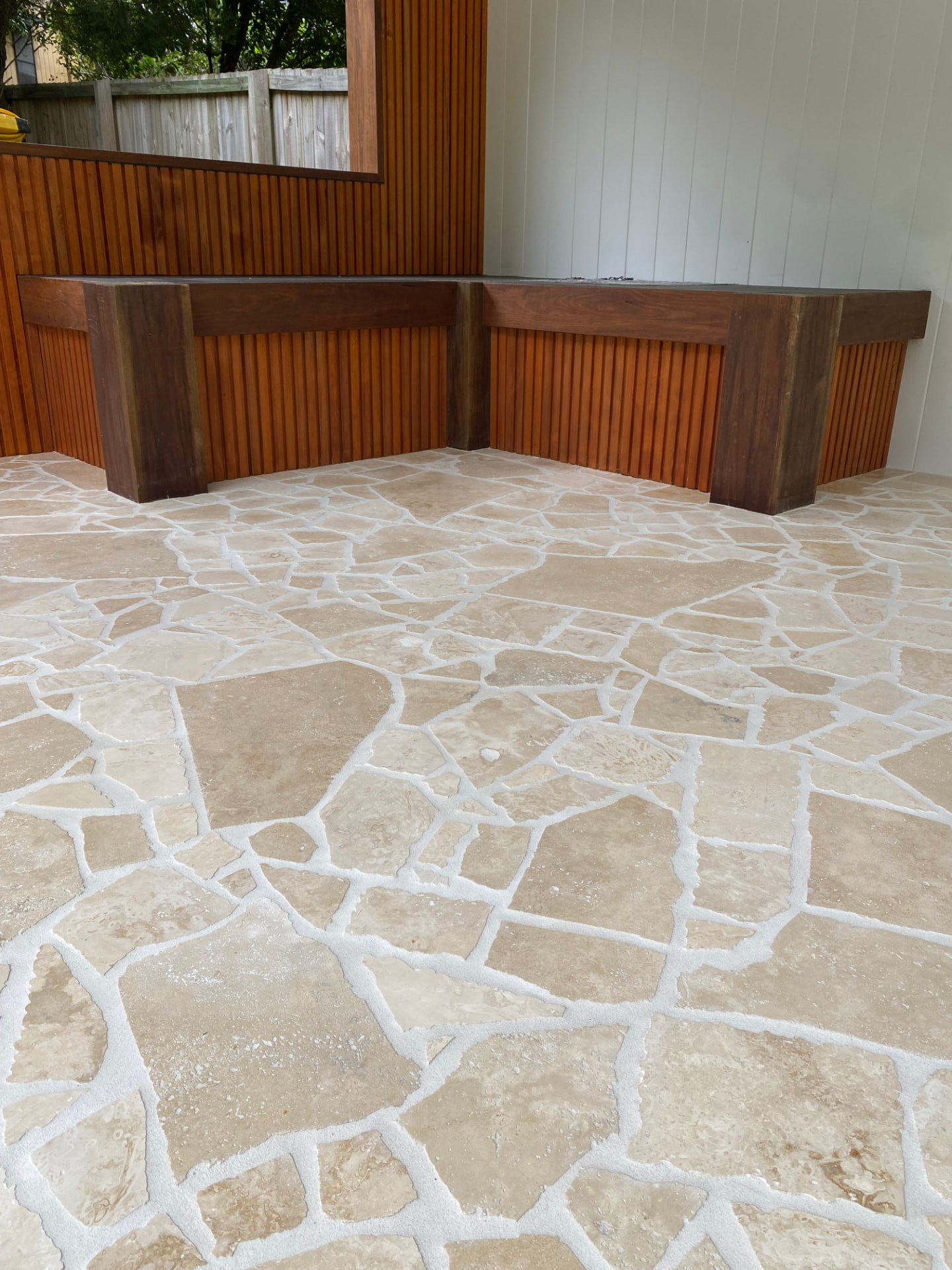 Summer Set travertine crazy paving in front of the hardwood bench and batten cladding